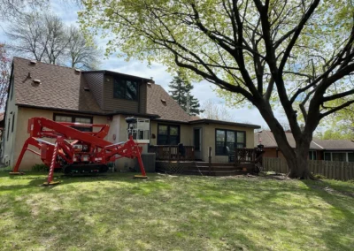 Backyard house with large tree and red aerial lift equipment