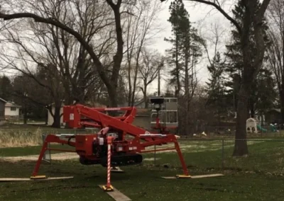 Red cherry-picker lift set up on grass under leafless trees