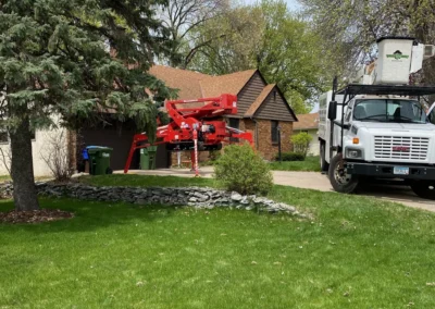 Tree service truck and red lift parked by suburban house driveway