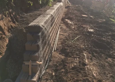 gabion retaining wall under construction along backyard slope